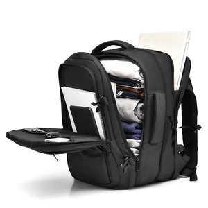 Grey travel backpack opened with laptop, clothes and gadgets packed inside