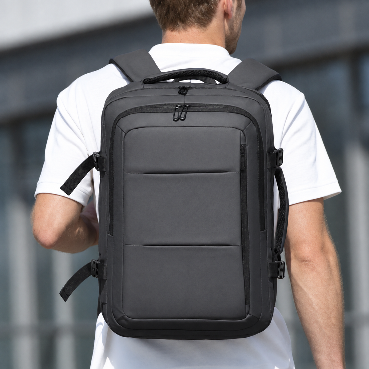 Man wearing the grey 40L expandable travel laptop backpack, back view